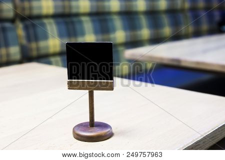Chalky wooden plaque on a table in a cafe for writing a table number. Moke up