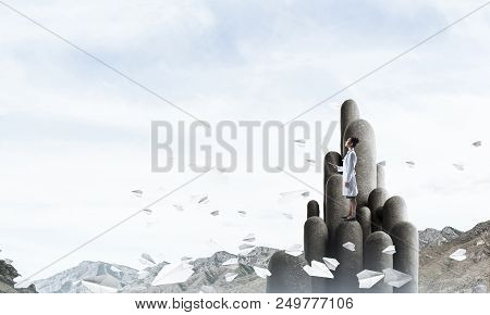 Young Female Doctor With Folder In Hands Satnding On Stone Column
