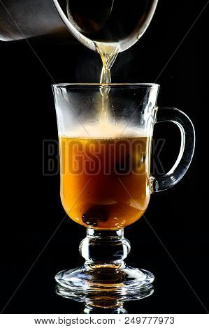 Process Of Preparing Hot Buttered Becherovka Cocktail With Honey, Cinnamon And Anise On Dark Backgro