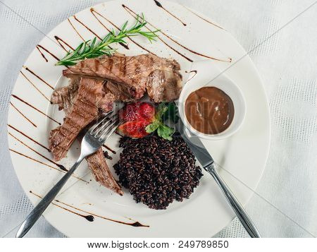 Appetizing Dish In A Restaurant: Juicy Mutton Ribs Of Medium Rare With Brown Rice, Strawberry And Sa