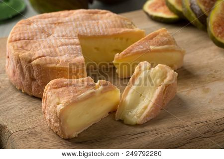 Piece of ripe petit Munster cheese close up and fresh figs on the background for dessert