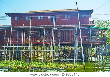 Traditional Wooden Stilt House With Poles For Mooring Canoes, Inpawkhon Village, Inle Lake, Myanmar.