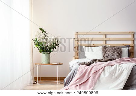 Wooden Bedhead With Lights By The Double Bed With Fur Pillow, Grey Sheets And Pink Blanket Standing