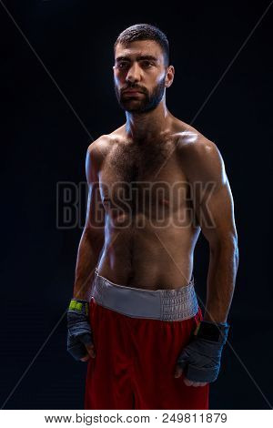 Handsome Athletic Guy In A Red Shorts On A Black Background. The Boxer Is Fetching His Breath After 