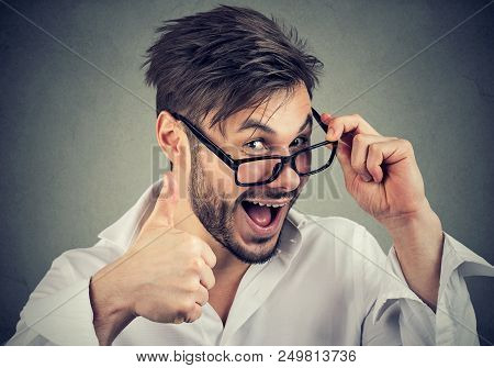Young Bearded Man In Glasses Showing Thumbs Up Gesture Looking At Camera With Overconfidence
