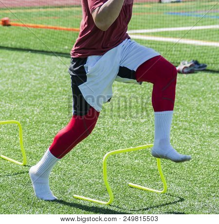 An Athlete Performs Speed And Agility Drills By Running Over Yellow Mini Hurdles Wearing Socks On A 