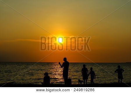 Silhouette People Play With Dog On Beach Sunset