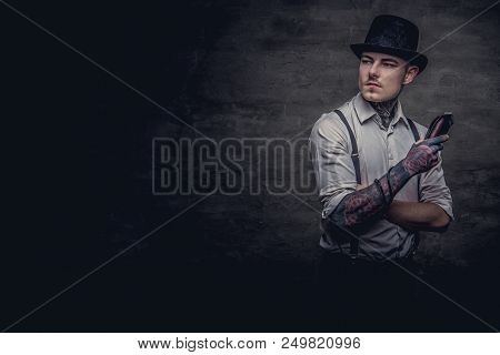 Portrait Of A Old-fashioned Tattooed Hairdresser Wearing A White Shirt With Suspenders And Cylinder 