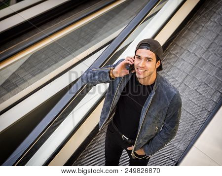 Young Trendy Man On Moving Walkway Or Travellator Or Autowalk, Looking Ata Camera