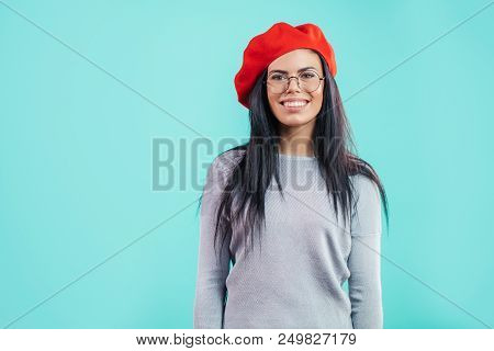 Elegant Young Smiling French Woman In Glasses On The Blue Background. Happy Foreign Tourist