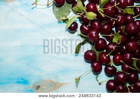 Beautiful Ripe Red Cherries On Blue Background With Copy Space