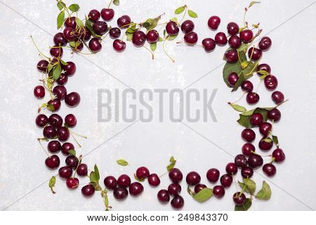 Frame Of Ripe Red Cherries On The Textured Gray Background With Copy Space