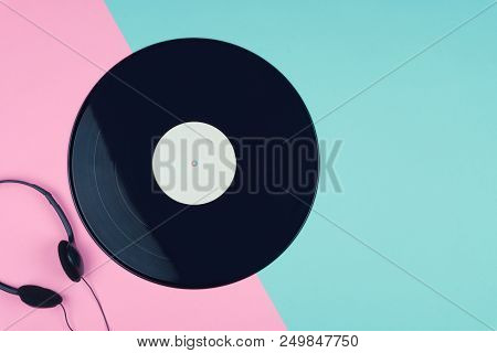 Top View Of A Long Play Vinyl Record Or Lp With A Black On-ear Headphone On The Pink And Blue Backgr