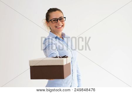 Jolly Smiling Girl In Glasses Giving Present. Happy Caucasian Woman Posing At Camera With Present Pa