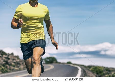 Runner athlete training on outdoor run with wearable tech smart watch working out cardio in intense exercise. Fit and healthy man.