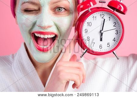 Facial Cosmetical Mask. Spa. Cosmetic Procedures. Woman With Cosmetic Mask On Face Holds Clock. Well