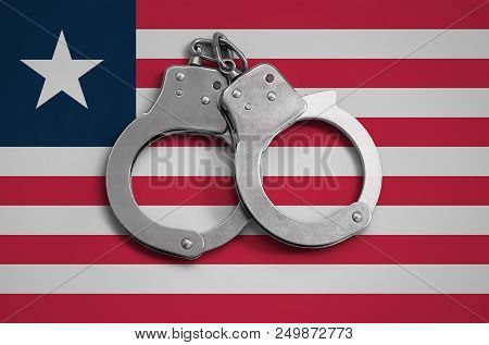 Liberia Flag  And Police Handcuffs. The Concept Of Observance Of The Law In The Country And Protecti