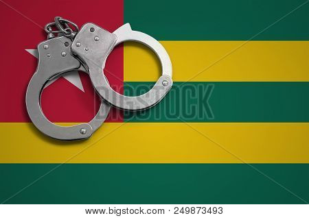 Togo Flag  And Police Handcuffs. The Concept Of Crime And Offenses In The Country.