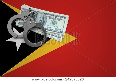 Timor Leste Flag  With Handcuffs And A Bundle Of Dollars. The Concept Of Breaking The Law And Thieve