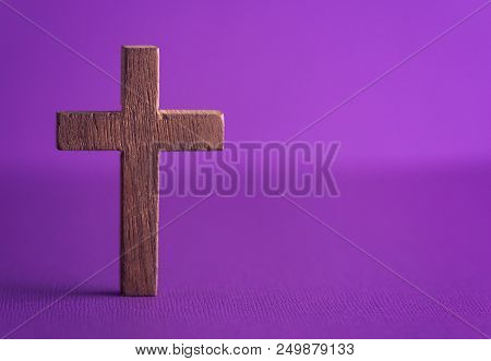 A Simple Wooden Cross On A Purple Background