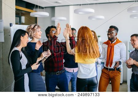 Hindo Guy And Caucasian Woman With Red Hair Are Giving High Five To Each Other With Two Hads Among T