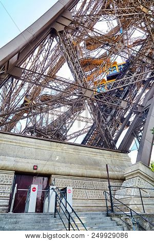 Yellow Diagonal Elevator Inside The Metal Support Of The Eiffel Tower. Support Base