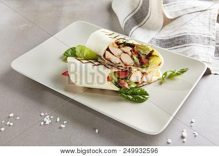 Chicken Shaverma or Doner Kebab with Vegetables on a White Plate Close Up. Rolls of Wheat Tortillas Stuffed with Turkey Fillet Cucumber, Tomato and Greens