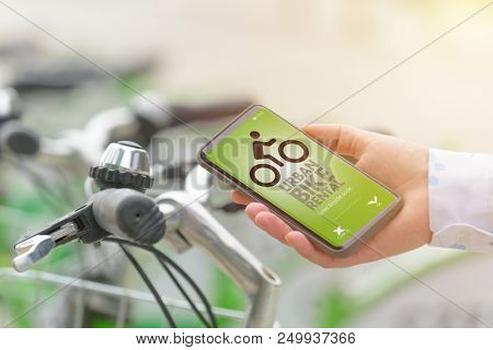 Woman using smartphone to rent bicycle from urban bicycle sharing station