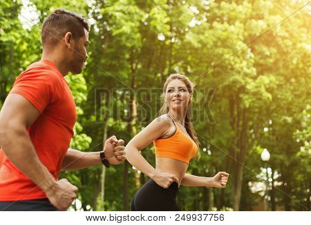 Athletic Couple Running Together Outdoots In Park In Sunny Summer Day
