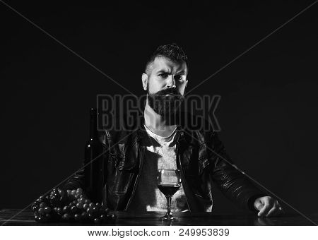 Sommelier Tastes Expensive Drink. Degustator With Serious Face Sits By Wine Bottle And Dark Grapes. 