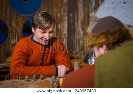 Two Men In Russian Ethnic Suit Playing Medieval Popular Strategy Board Game - Tafl. Folk, Competitio