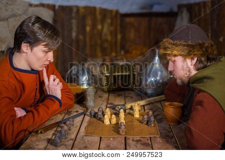 Two Men In Russian Ethnic Suit Playing Medieval Popular Strategy Board Game - Tafl. Folk, Competitio