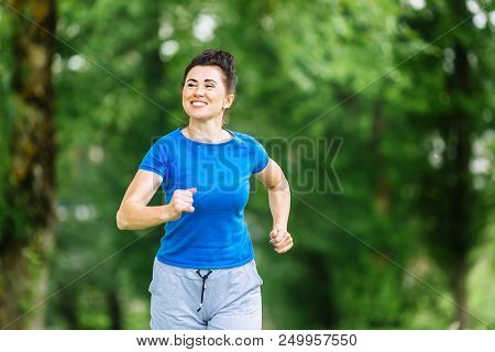 Smiling Senior Woman Running In Park. Heathy Life Style Concept.