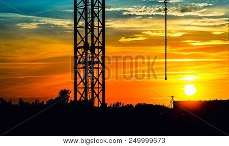 Sunset Over The City With A Crane Silhouette