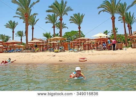 Hurghada / Egypt. 30 July 2018: Little Girl Swimming In Water Lying On Inflatable Circle During Summ