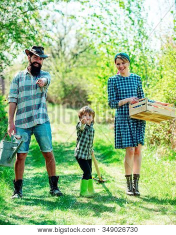 Happy Family: Mother, Father, Children Son On Spring Garden Background. Family Gardening In The Back