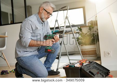 Man at home using electric drill, do-it-yourself work