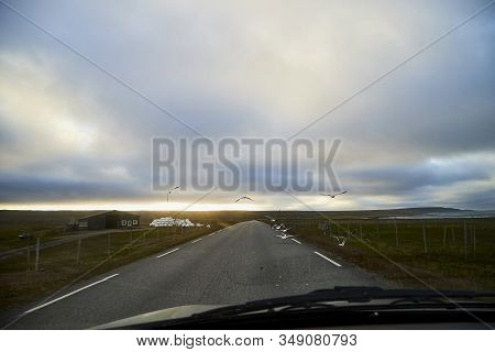 View On Grey Road, Yellow Surise And Dramatic Clouds From The Car Front Window In Early Mourning. Dr