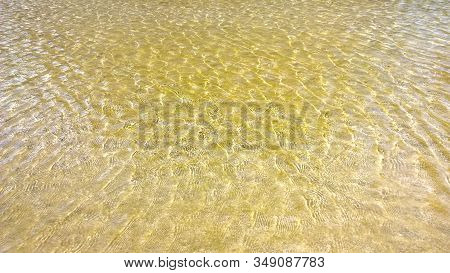 Waves Of Golden Sea Water On Beach With Sun Reflection