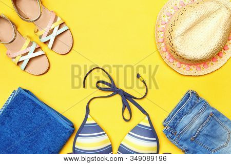 Summer Beach Accessories On A Yellow Background. Hat, Shorts, Bikini, Towel And Sandals. Top View Co