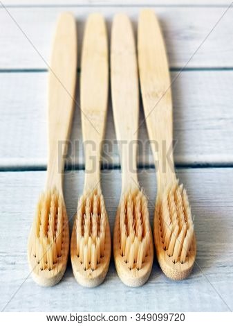 A Family Set Of Four Wooden Toothbrushes On White Wooden Background With Copy Space