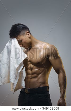 Tired Muscular Asian Man Indoors Against Grai Background