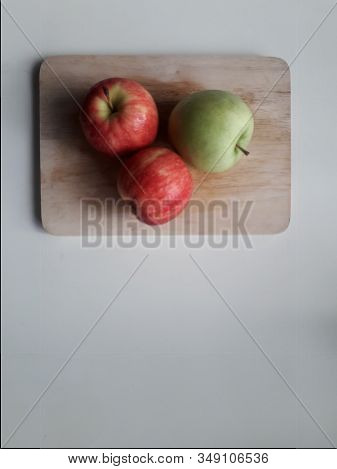 1 Green Apple And 2 Red Apples On The Cutting Board