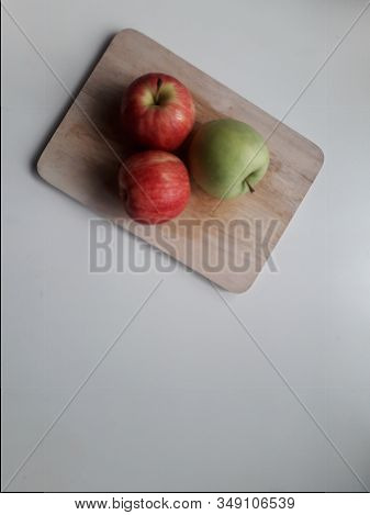 1 Green Apple And 2 Red Apples On The Cutting Board