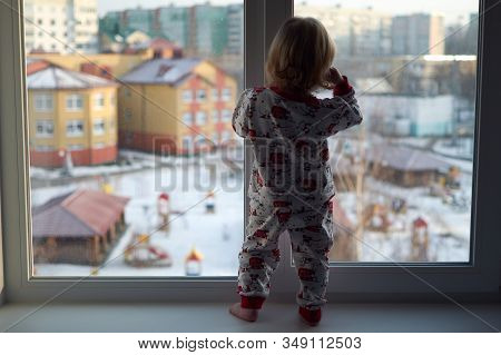 A Little Girl Standing In Front Of A Window