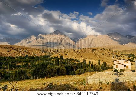House With Mountain Background Behind With Clouds On The Sky, Turkey
