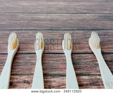 A Family Set Of Four Wooden Toothbrushes On Wooden Background With Copy Space