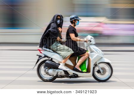HANOI, VIETNAM â APRIL 02 2018: Local people wearing facemasks and riding moped or scotter on the streets of Hanoi, Vietnam, South East Asia