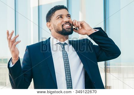 Cheerful Businessman Talking On Phone And Celebrating Good News And Success. Young Latin Man In Form