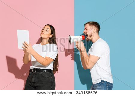 No Selfie. He Tries To Pay Her Attention. Young, Happy Man And Woman In Casual Clothes On Pink, Blue